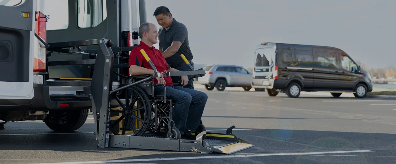 Wheelchair passenger being lifted into the back of a full size white van